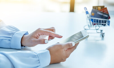 Consumer woman hand use smart phone and a mock up credit card, ready to spending pay online finance shopping according to discount products from home office