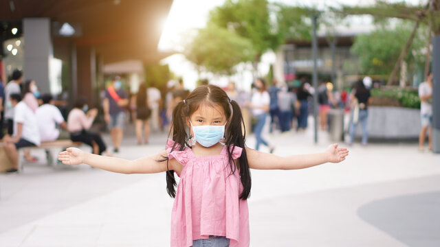 Asian Child Or Kid Girl Wearing Blue Face Mask And Open Arm To Present Or Stop No Entry On Lot Of People For Social Distancing On Shopping Mall Or Department Store On Holiday By Coronavirus Covid-19