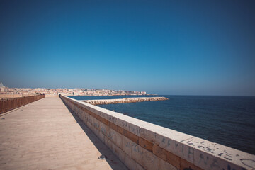 A walk with the view of the city and harbor of Syracuse seen from Isola di Ortigia's walls