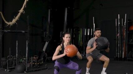 Beautiful young sports couple is working out with medicine ball in gym slow motion.