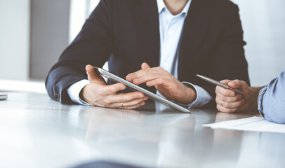 Business people using tablet computer while working together at the desk in modern office. Unknown businessman or male entrepreneur with colleague at workplace. Teamwork and partnership concept