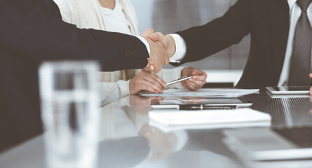 Business people shaking hands after contract signing in modern office. Teamwork and handshake concept