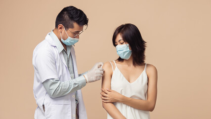 Asian people, Man doctor wearing medical mask and gloves putting a bandage on arm of woman after a getting coronavirus (COVID-19) vaccination.