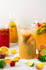 Fototapeta na wymiar Jugs of fresh refreshing fruit drinks with fruit wedges, summer cold juices with ice