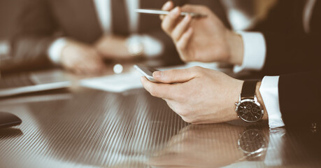 Unknown businessmen and woman sitting, working and discussing questions at meeting in modern office, close-up