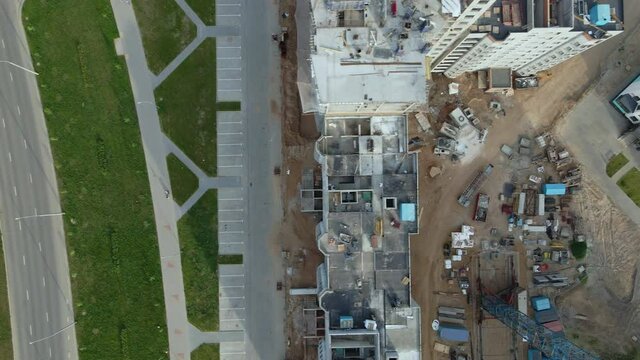 Aerial photography of the construction site. Construction of modern multi-storey buildings. Flying sideways over rooftops with a lowered camera.