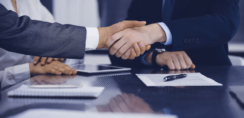 Handshake as successful negotiation ending, close-up. Unknown business people shaking hands after contract signing in modern office - obrazy, fototapety, plakaty