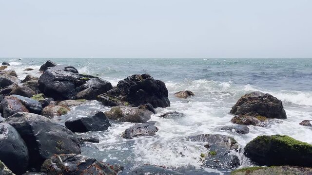 Sea waves collide against coastal rocks.