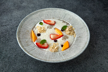 Healthy vegetarian wholesome breakfast porridge with berries, fruits and chia seeds. Ready menu for the restaurant. Neutral gray blue textured background