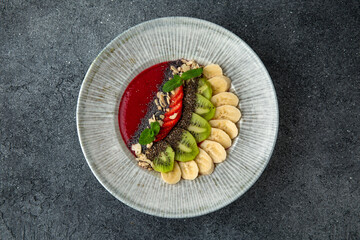 Healthy vegetarian wholesome breakfast chia seed porridge with berries, fruits and nuts and strawberry puree. Ready menu for the restaurant. Neutral gray blue textured background