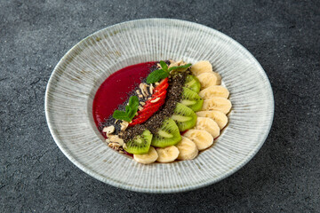 Healthy vegetarian wholesome breakfast chia seed porridge with berries, fruits and nuts and strawberry puree. Ready menu for the restaurant. Neutral gray blue textured background