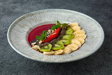 Healthy vegetarian wholesome breakfast chia seed porridge with berries, fruits and nuts and strawberry puree. Ready menu for the restaurant. Neutral gray blue textured background