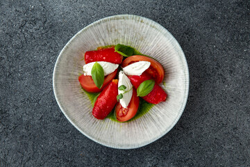 Tomato with Baked Bell Pepper and Cheese. Ready menu for the restaurant. Neutral gray blue textured background.