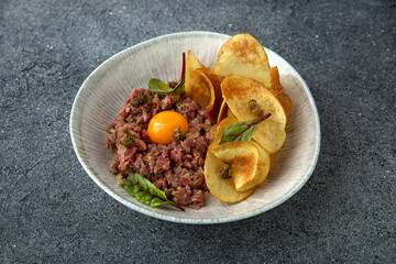 Tar tar beef with cappers and egg. Ready menu for the restaurant. Neutral gray blue textured background