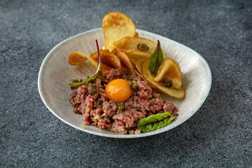 Tar tar beef with cappers and egg. Ready menu for the restaurant. Neutral gray blue textured background