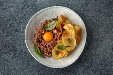 Tar tar beef with cappers and egg. Ready menu for the restaurant. Neutral gray blue textured background