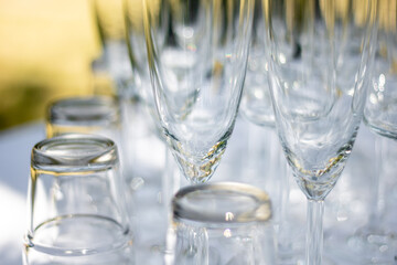 Close up of various glasses, champagne glasses and cocktail glasses on a table with white tablecloth, focus on Champagne glasses