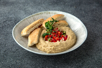 Hummus with baked bell peppers. Ready menu for the restaurant. Neutral gray blue textured background