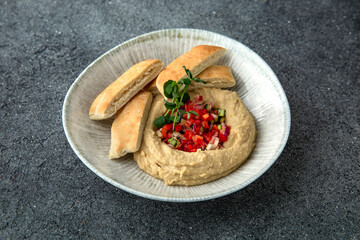 Hummus with baked bell peppers. Ready menu for the restaurant. Neutral gray blue textured background