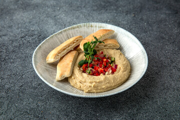 Hummus with baked bell peppers. Ready menu for the restaurant. Neutral gray blue textured background
