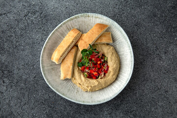 Hummus with baked bell peppers. Ready menu for the restaurant. Neutral gray blue textured background