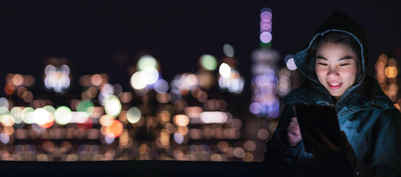 adult asian female traveller casual cloth hand use smartphone tablet device communication with cheerful and happiness with background of urban city light bokeh lifestyle ideas concept