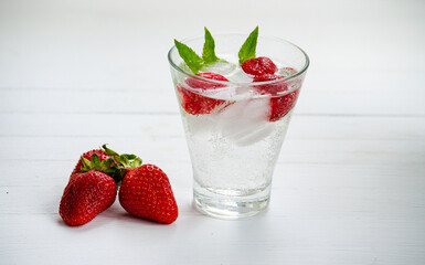 Summer refreshing transparent cocktail with soda, strawberries, mint and ice.