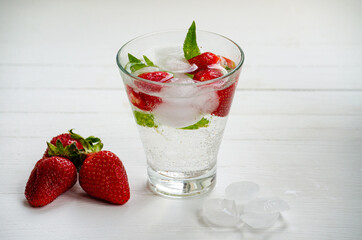 Summer refreshing transparent cocktail with soda, strawberries, mint and ice.