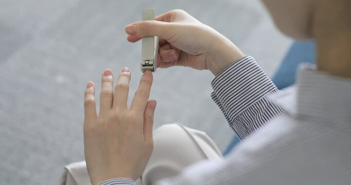 A woman's hand that cuts her nails with a nail clipper
