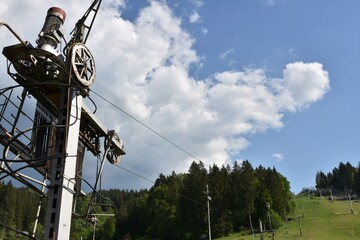 Close up view on mechanism of surface lift which pull up skiers uphill in abandoned ski area, Jasenska dolina in the Turiec region, Slovakia, during summer. Hill is covered with green grass. © Lucia