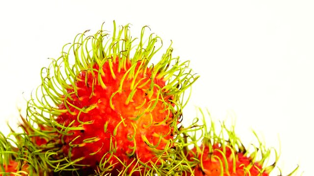 4K  whole red freen color rambutan fruits and one peeled rambutan. Rotating on the turntable isolated on the white background. Close up. Macro