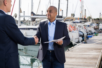 two men in suits buy and sell a yacht in the seaport