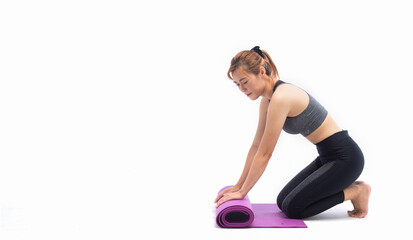 Fototapeta na wymiar Young lady in grey sportwaers rolling yoga mat at home on white background