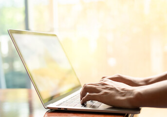 man is using a laptop to search for business information, stocks on desk and communicate using social media with colleagues using the Internet. Closeup hands typing keyboard and free copy space