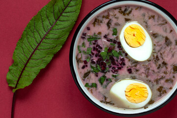 Sorrel soup with halved egg in enamel bowl. Flat lay top view.