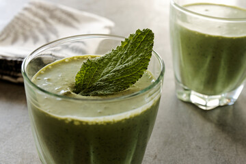 Close view of green smoothie with herb leaves in glass. Green beverage with borage healthy plant.