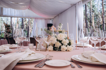 Wedding table setting and decoration. Candles and cutlery on the table. Flower decoration of the banquet hall.
Pink background.