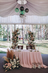 Bride and groom table setting and flower decoration. Presidium of newlyweds outdoors. Cutlery on the table. Floral decorations.
