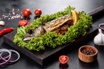 Baked mackerel with vegetables on a wooden board with lemon