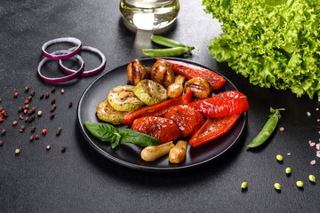 Tasty fresh vegetables grill: tomatoes, peppers, mushrooms, zucchini and onions on a black plate