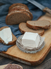 Fototapeta na wymiar A slice of butter on a background of rye bread on a cutting board.