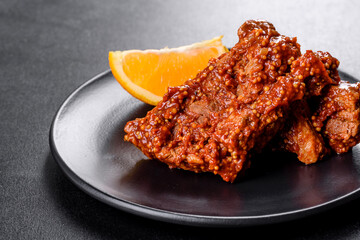 Delicious fresh baked pork ribs with orange on a black plate