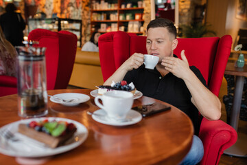 Young man enjoying cup of coffee in lonely reverie at table of a cozy cafe