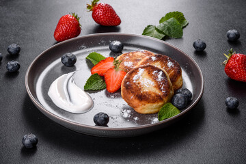 Tasty baked pancakes with berries and mint with powdered sugar and topping on a gray plate