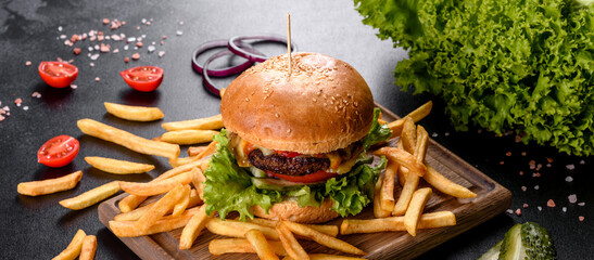 Delicious fresh burger with beef cutlet, tomatoes and lettuce with french fries