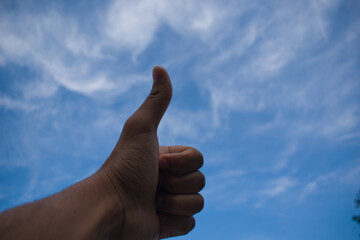 Thumbs up with left hand to dark blue sky