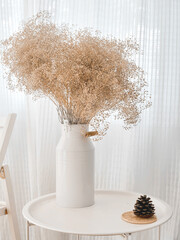 Dry decorative flower branches in a white vase on the circle table