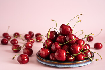 Fresh  ripe cherry on plate on pink background. Copy space.