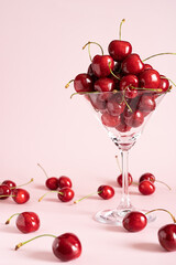 Fresh  ripe cherry in glass on pink background. Copy space.