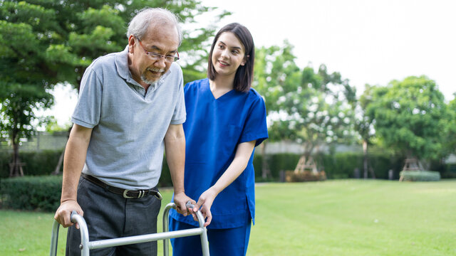 Asian Senior older man walk in public park with carer nurse's support.